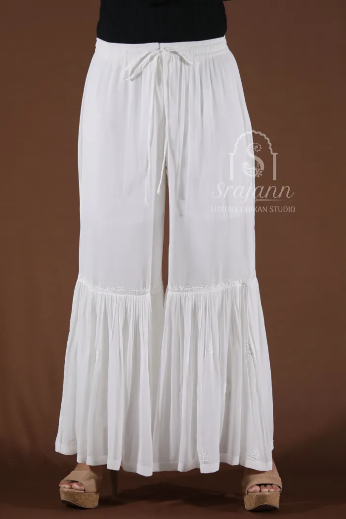 A pair of white cotton straight pants with intricate hand-embroidered Lucknowi Chikankari.